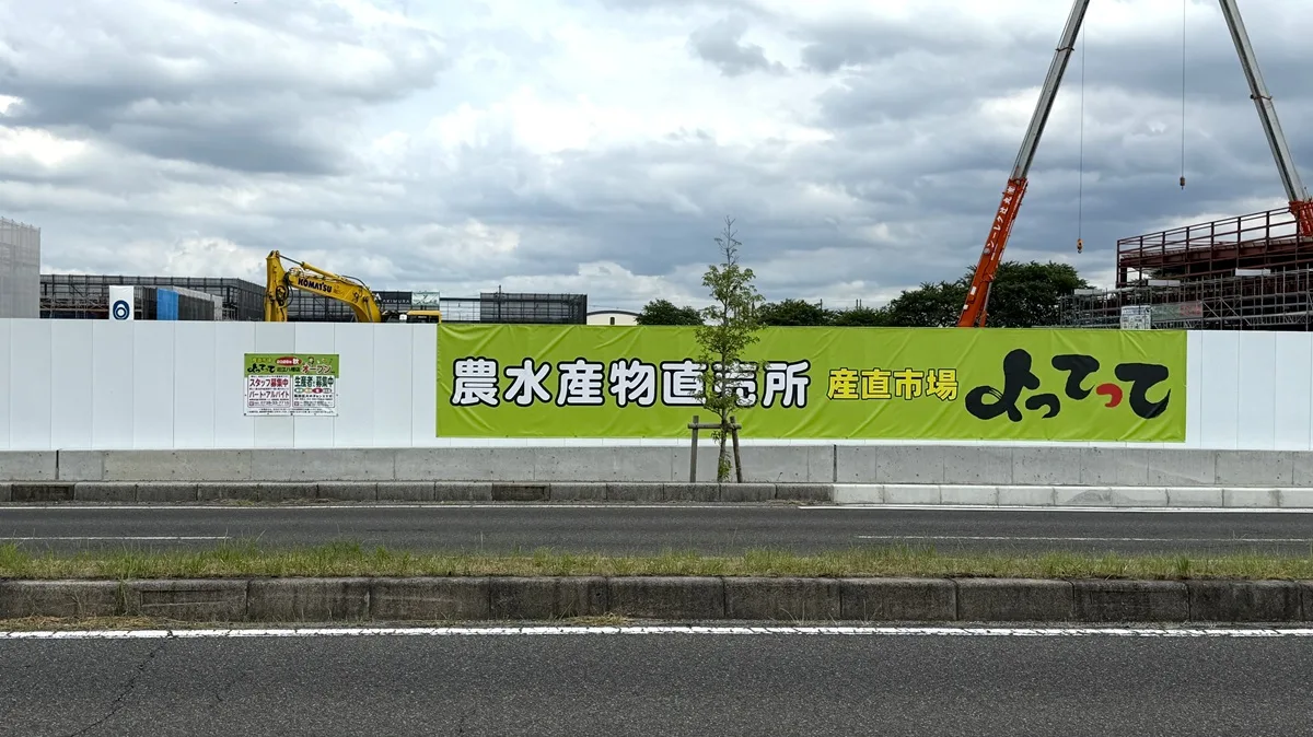近江八幡市土田町に建設中の複合商業施設「クロスモール近江八幡」の工事現場を現地確認してきました。写真は2026年6月18日に撮影。「産直市場よってって」の大きな広告。